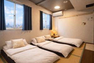 a room with four beds in it with a window at 心斎橋難波関空直通 Ambers Hostel in Osaka