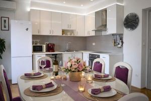a white kitchen with a table with flowers and candles at Apartments Karla in Stanići