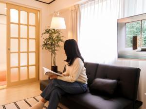 a woman sitting on a couch reading a book at Atelier7419 Songpa in Seoul