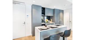 a kitchen with blue cabinets and a white table and chairs at Luxe 46th Level 2 Bedroom CBD Apartment with Pool Gym Spa and Views in Melbourne