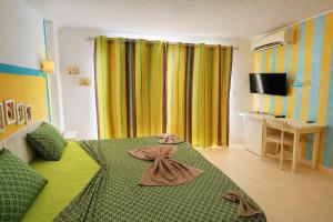 a bedroom with a green bed and yellow curtains at Pensão Big Game Maio Vila do Maio in Vila do Porto
