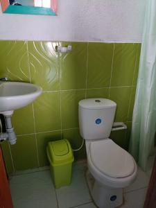 a green bathroom with a toilet and a sink at Casa hostal playa coral in Capurganá +31 photos