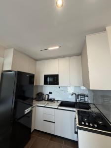 a kitchen with white cabinets and a black refrigerator at Rapo Apartment in Krujë