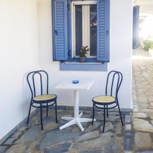 two chairs and a white table and a window at Kampos Bliss Studios in Votsalákia