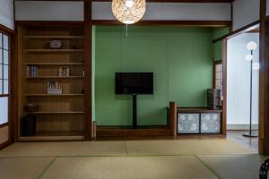 a living room with a tv and a green wall at 一棟貸しの宿 Granny and the sea グラニーアンドザシー in Shima