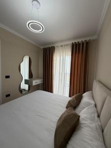 a bedroom with a large white bed and a window at Rapo Apartment in Krujë