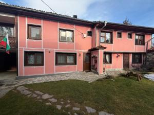 a pink house with a yard in front of it at Nenchova Guest House in Koprivshtitsa