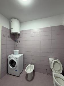 a bathroom with a toilet sink and a washing machine at Rapo Apartment in Krujë +9 photos