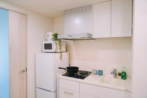 a white kitchen with a stove and a white refrigerator at Sky Home新宿 in Tokyo