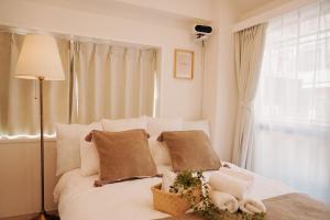 a bedroom with a white bed with pillows and a window at Sky Home新宿 in Tokyo