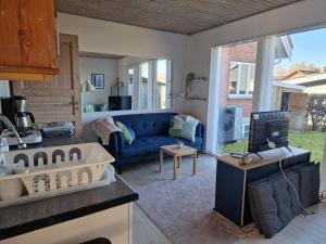 a living room with a blue couch and a tv at Lillebo fred og ro in Græsted