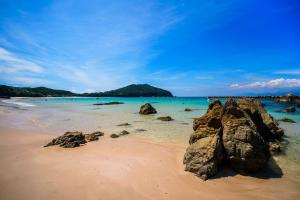 a beach with rocks in the sand and the ocean at 一棟貸しの宿 Granny and the sea グラニーアンドザシー in Shima