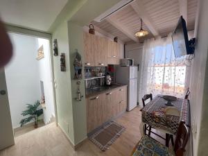 a small kitchen with a table and a refrigerator at La Terrazza Solarium, in pieno centro 60m dalla stazione ferroviaria 700m dal mare in Santa Flavia