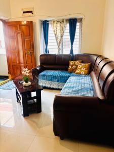 a living room with a leather couch and a table at Indigo Homes Kondapur in Hyderabad +3 photos