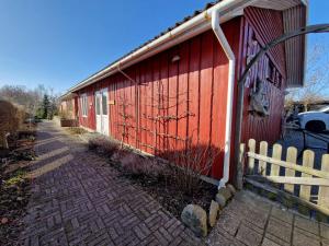 a red building with a fence next to a sidewalk at Lillebo fred og ro in Græsted
