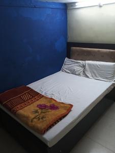a small bed with a blanket on top of it at Shri Krishna Guest House in Mathura