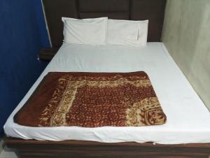 a bed with a brown and white blanket on it at Shri Krishna Guest House in Mathura
