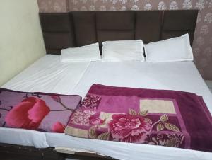 a bed with a blanket and pillows on it at Shri Krishna Guest House in Mathura