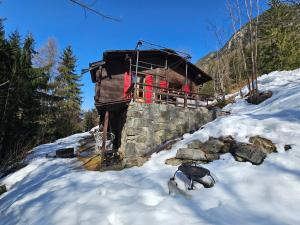 a log cabin with a red balcony in the snow at Petit chalet rustique et bucolique in Bovernier