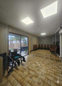 an empty waiting room with chairs and tables in a building at Hôtel Myosotis in Lourdes