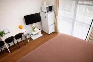 a kitchen with a refrigerator and a table and chairs at ひまわり in Dazaifu