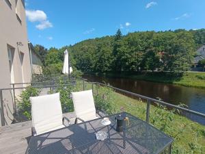a patio with two chairs and a table next to a river at Otava apartments - Rezidence Valcha in Sušice