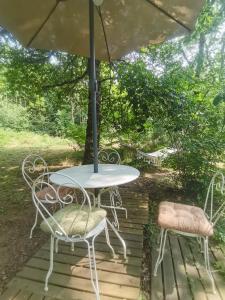 a table and two chairs on a deck with an umbrella at La Verdine in Lacaze