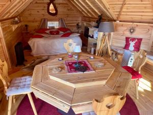 a room with a wooden table in a cabin at KOTA bien être jaccuzzi , sauna , piscine chauffée , soins bien être in Voissant
