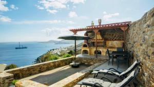 a patio with a table and chairs and an umbrella at Vignetta Mare 2BR Villa με Θέα & και Ιδιωτικό Πάρκινγκ in Ermoupoli