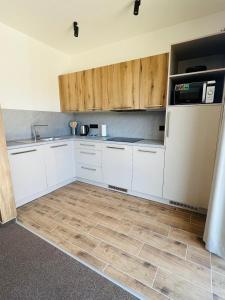 a kitchen with white cabinets and a wooden floor at Apartmány Stagnum Liptovský Ján in Liptovský Ján