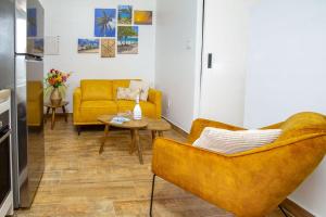 a living room with a yellow couch and a table at Loveli Stay Aruba in Oranjestad
