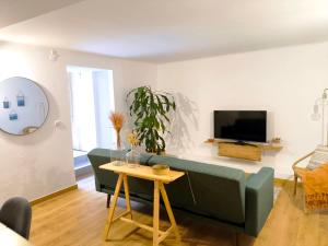a living room with a green couch and a tv at O Refúgio do Pim in Horta