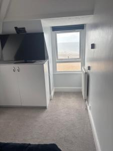 a room with a television and a window with the beach at Navigator Hotel in Bognor Regis