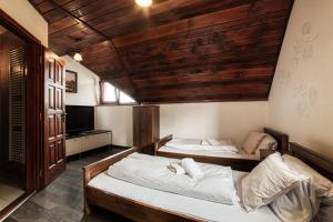 two beds in a room with wooden ceilings at Penzión Jolla in Červený Kláštor