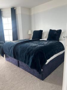 a bedroom with a large bed with a blue blanket at Navigator Hotel in Bognor Regis