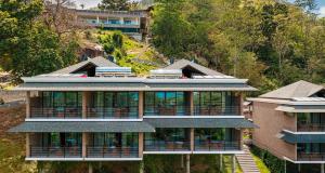 a large house on a hill with trees and a building at Gardens Hill Resort & Spa in Beau Vallon