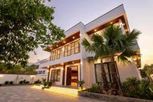 a white house with a palm tree in front of it at Blanc Smith Private Villa in Siem Reap