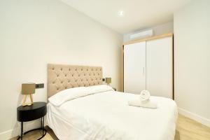 a white bedroom with a large bed and a window at Rosario 32 by keyhom in Salamanca