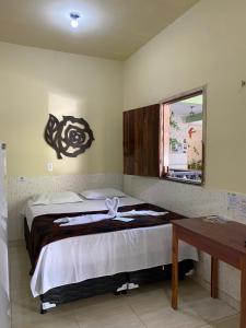 a bedroom with a bed and a desk and a window at Pousada Preocupacao Zero in Ubajara