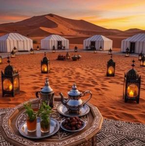 a table in the desert with food on it at Merzouga Nice luxury Camp in Merzouga
