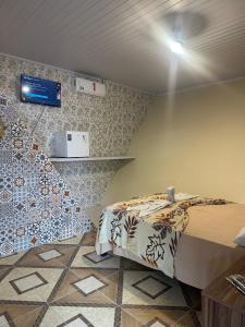 a small room with a bed and a tv on the wall at Pousada Preocupacao Zero in Ubajara