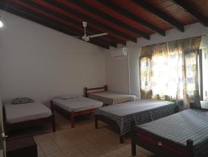 a room with three beds and a window at Posada El Descanso in Caacupé
