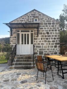 a stone house with a table and chairs in front of it at Sasovici farmstay in Magazini