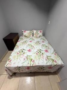 a bed with a floral comforter in a bedroom at Casa Ibirapuera in Vitória da Conquista