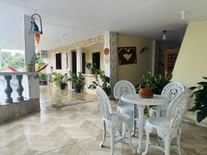 a patio with white chairs and a table and a room at Pousada Preocupacao Zero in Ubajara