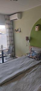 a bedroom with a bed with a green headboard and a table at Biesbosch Bed & Breakfast Werkendam in Werkendam