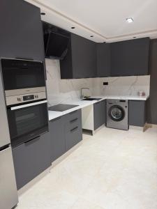 a kitchen with black cabinets and a washer and dryer at Luxe Appartement Haut Standing Nador Lagoon Rif in Nador +28 photos