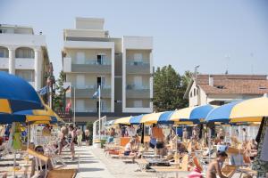 a beach with people sitting on chairs and umbrellas at Hotel Gigliola in Bellaria-Igea Marina