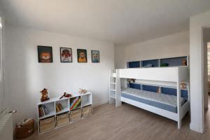 a white room with two bunk beds and shelves at L'entracte in Clairvaux-les-Lacs