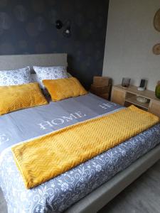 a bed with a yellow and blue blanket on it at le gite de margot in Beyssac